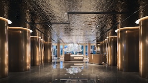 A modern hotel lobby with a reflective floor, large cylindrical columns, and a central seating area with a chandelier. - Hotel Indigo Hangzhou Tianmushan by IHG (Hangzhou)