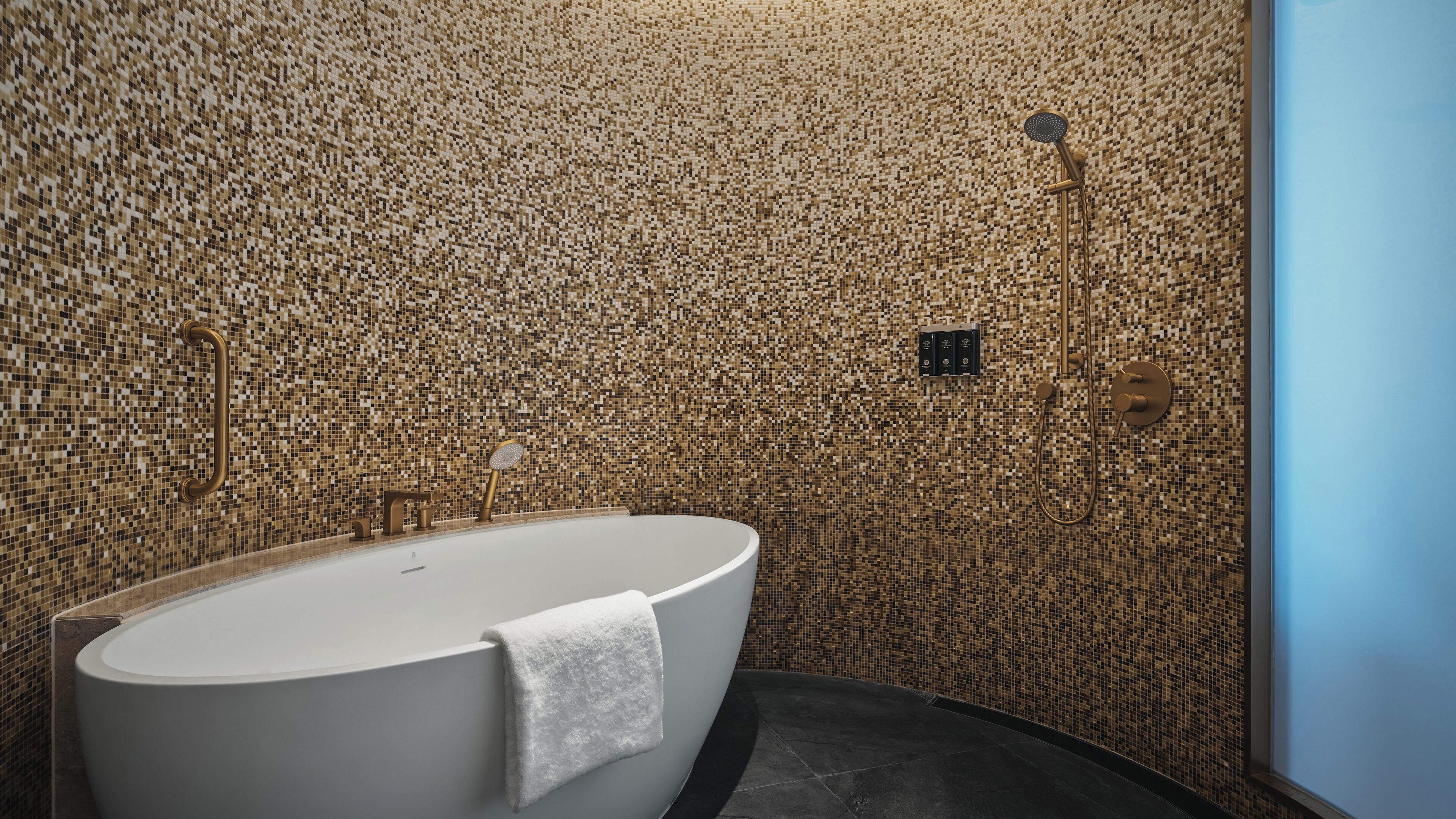 Un baño moderno con una bañera independiente, zona de ducha y pared de mosaico.