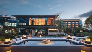 A modern multi-story building with a spacious outdoor seating area, a fire pit, and well-lit pathways. - Hotel Indigo Hangzhou Tianmushan by IHG (Hangzhou)