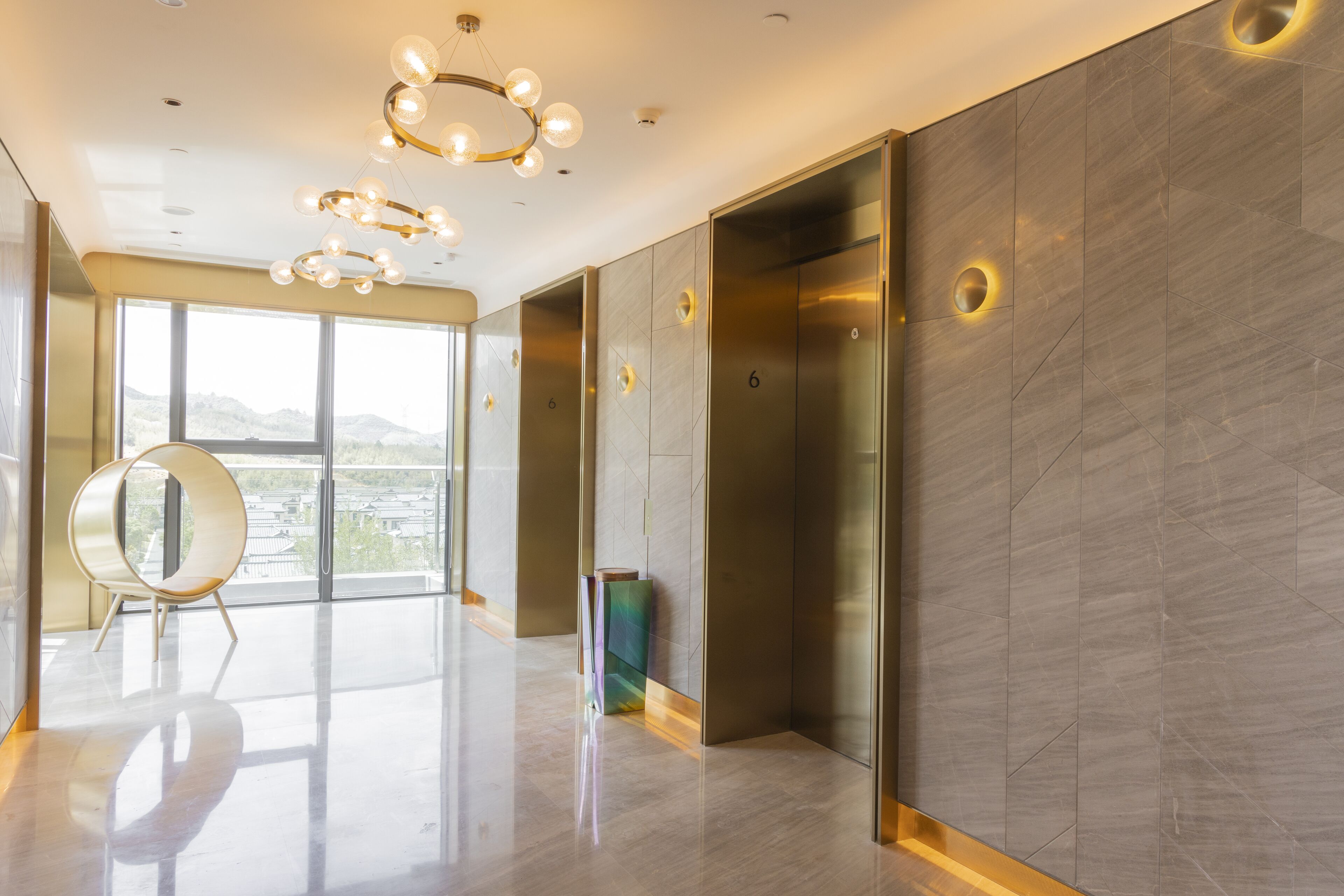 Un ascensore moderno con finiture metalliche, porta in vetro e parete decorata con motivi geometrici.