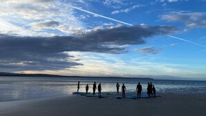 A beach with people standing on surfboards, a clear sky, and a visible contrail. - 10 minutes from the local beach great surfing beach
License Nr.HI-00282-F (Thurso)