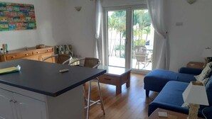 A room with a kitchen area, a dining table, a blue sofa, and a small wooden table with a lamp. -  3 bed 3 bath villa on the west coast (Saint James)