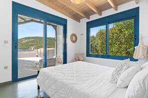 Une chambre avec un grand lit, une vue sur un jardin par la fenêtre et une porte donnant sur un espace extérieur.