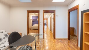 A modern hotel room with a glass table, wooden flooring, and a view of the hallway. - Txurruka - baskeyrentals (Mutriku)