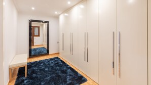 A hallway with a mirror, a bench, and a wardrobe with multiple doors. - Txurruka - baskeyrentals (Mutriku)