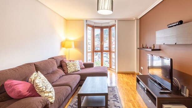 A living room with a sofa, coffee table, TV, and a lamp. - Txurruka - baskeyrentals (Mutriku)