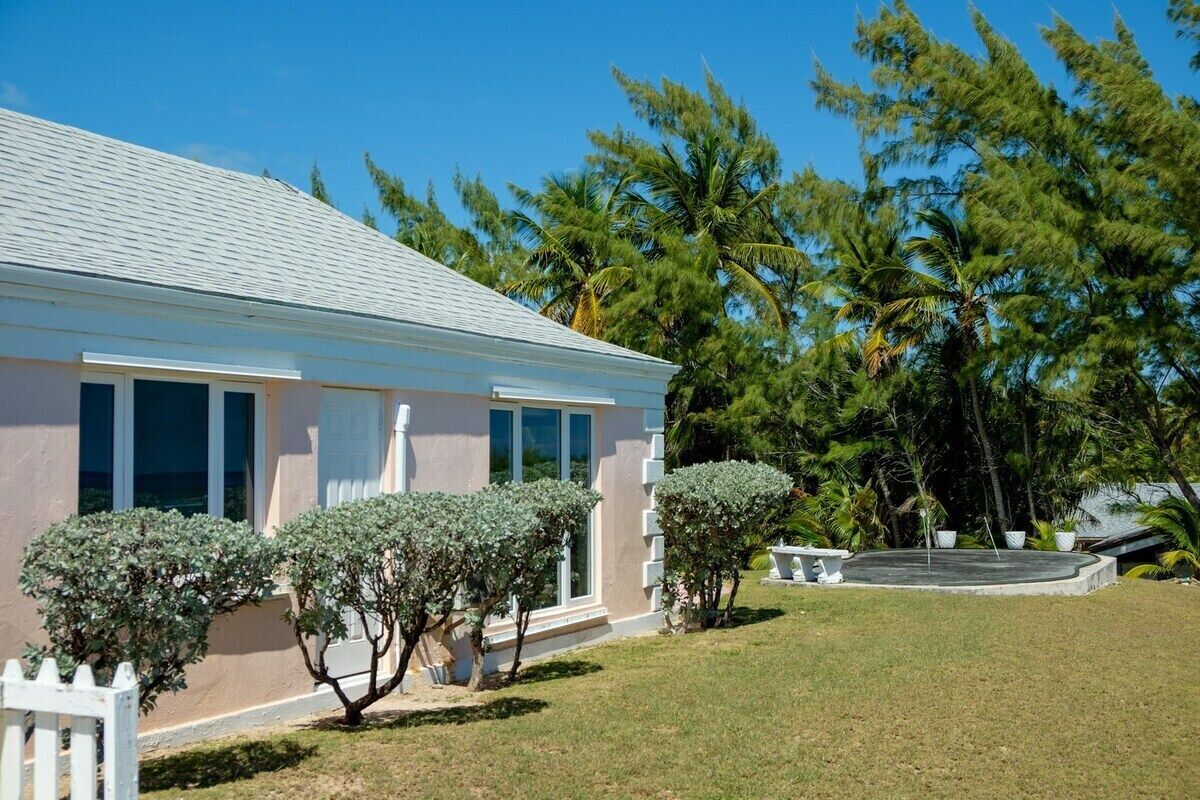A single-story house with a light-colored exterior, a white picket fence, and a well-maintained lawn.