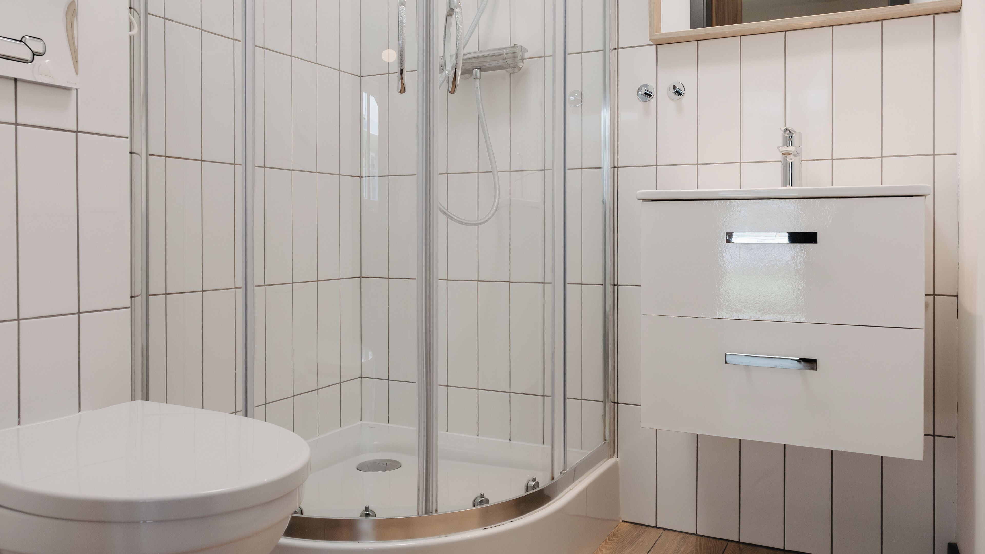 A modern bathroom with a glass-enclosed shower, a toilet, and a cabinet with drawers.