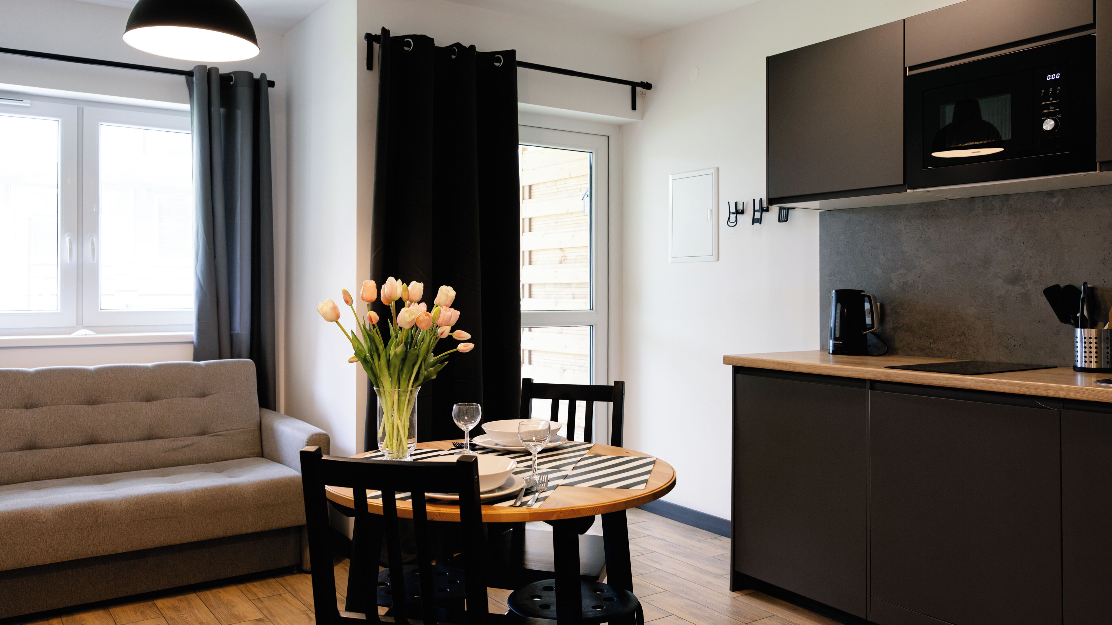 Een moderne keuken met een eethoek, een bank en een raam met gordijnen.