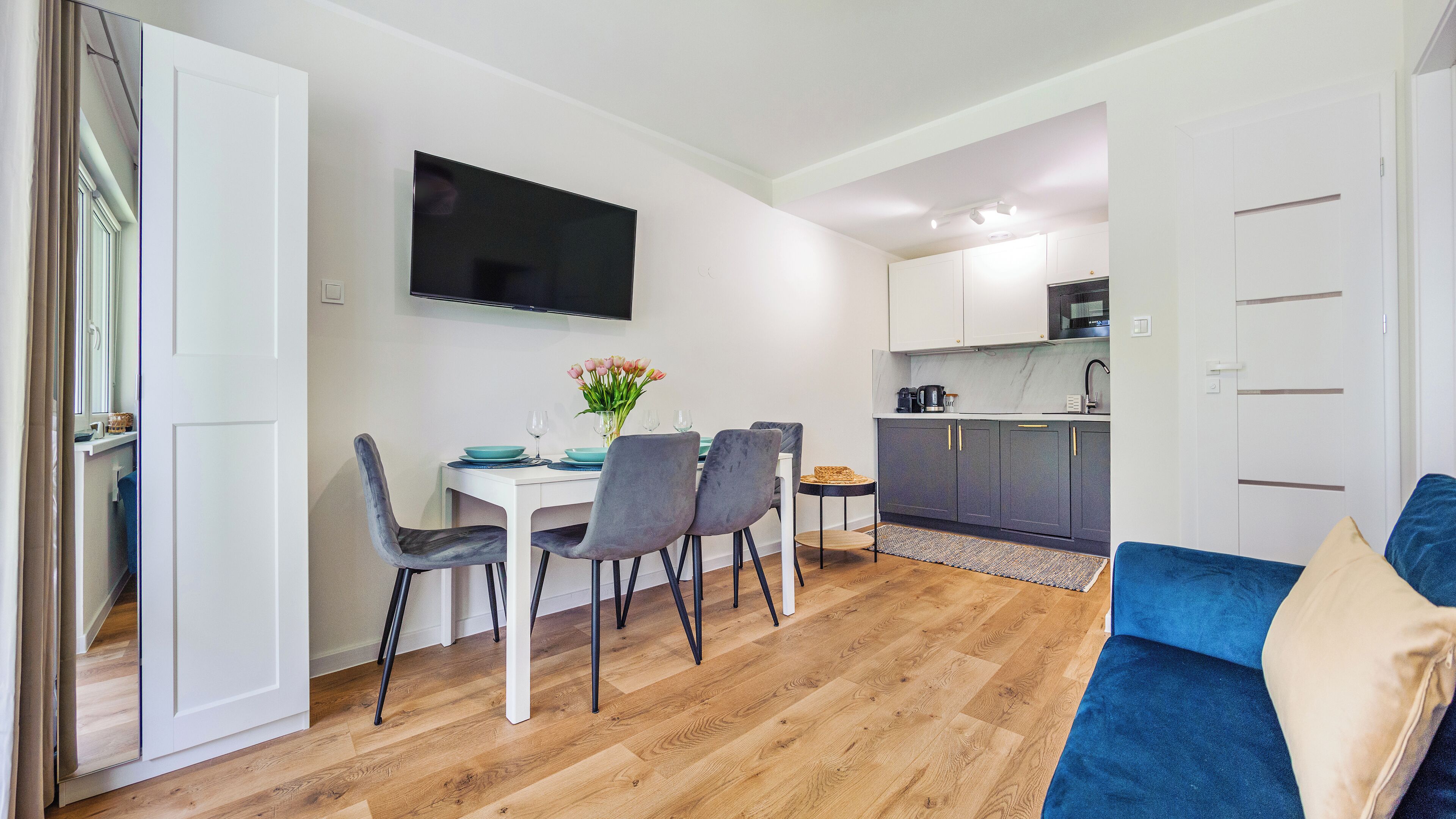 A compact living space with a dining area, kitchenette, and a sofa.