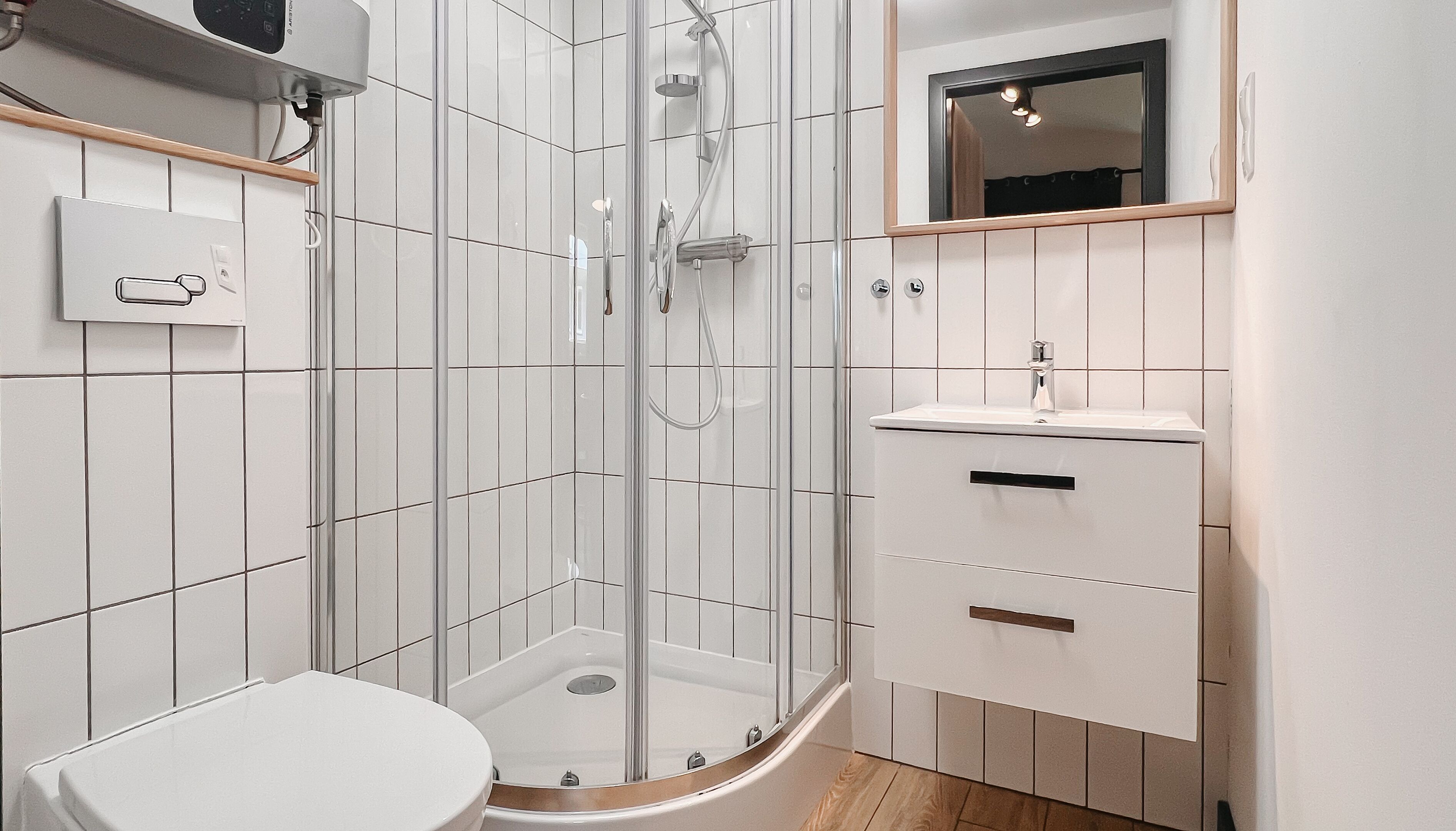 A modern bathroom with a glass-enclosed shower, a white toilet, and a vanity with a mirror.