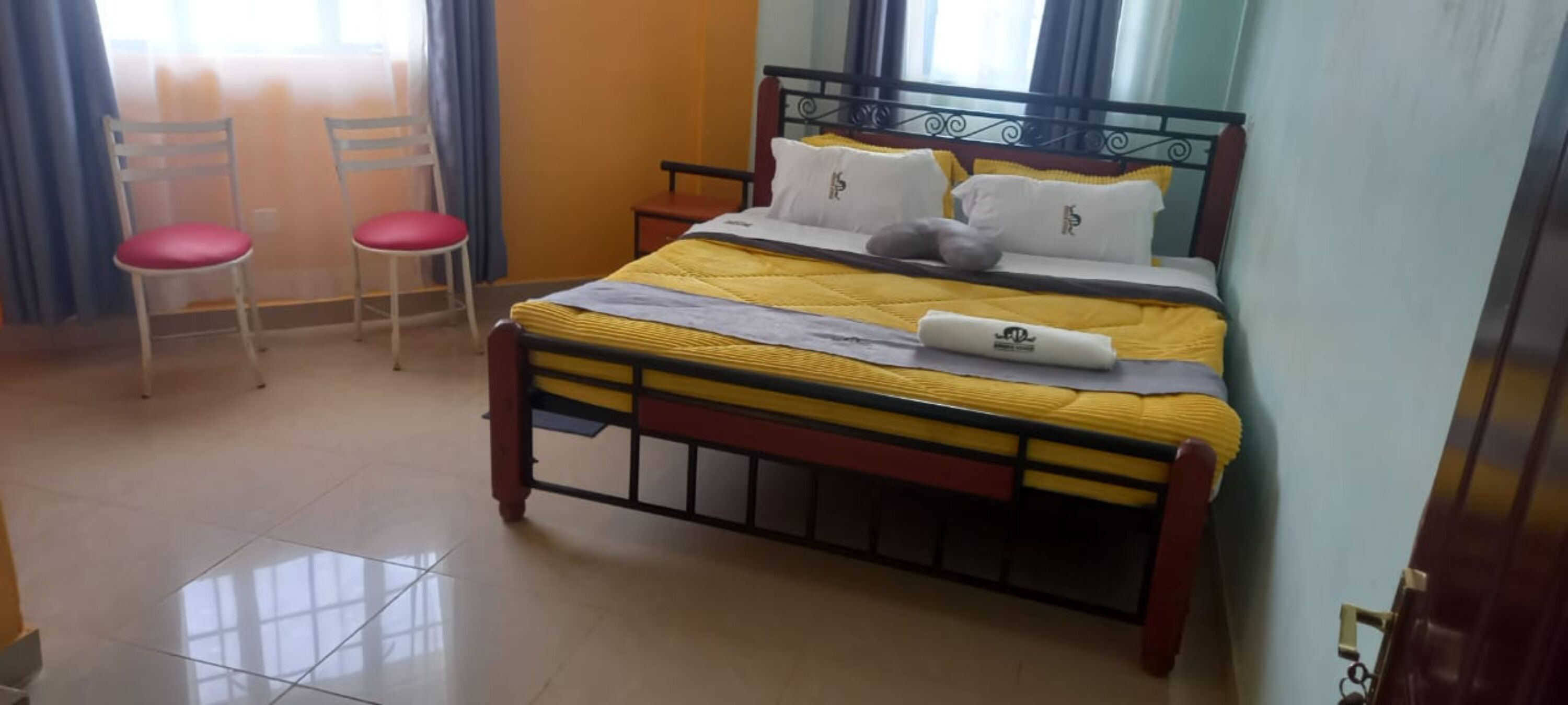 A bedroom with a bed, two chairs, and a window.