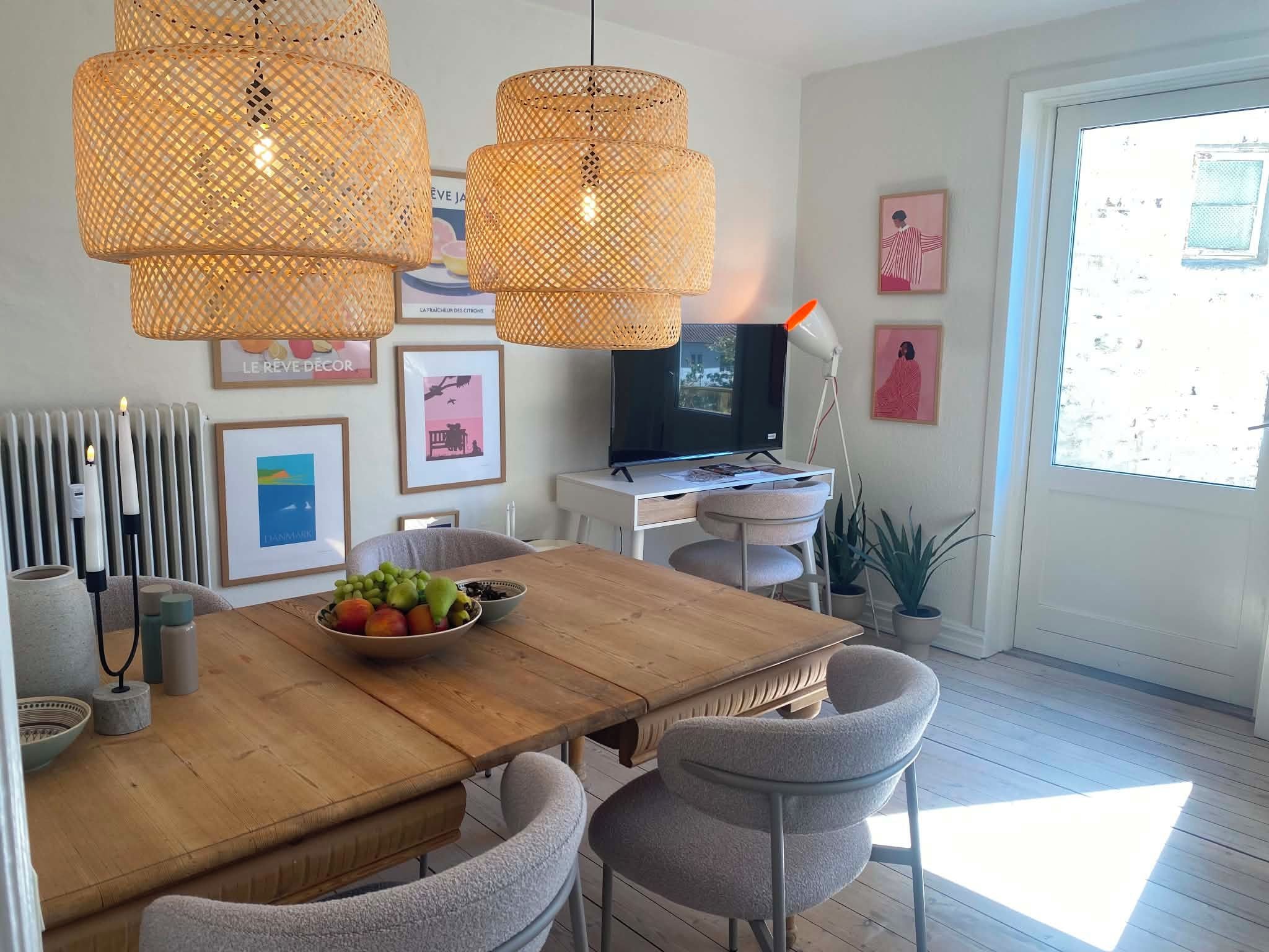 Un comedor moderno con una mesa de madera, sillas grises y un frutero.
