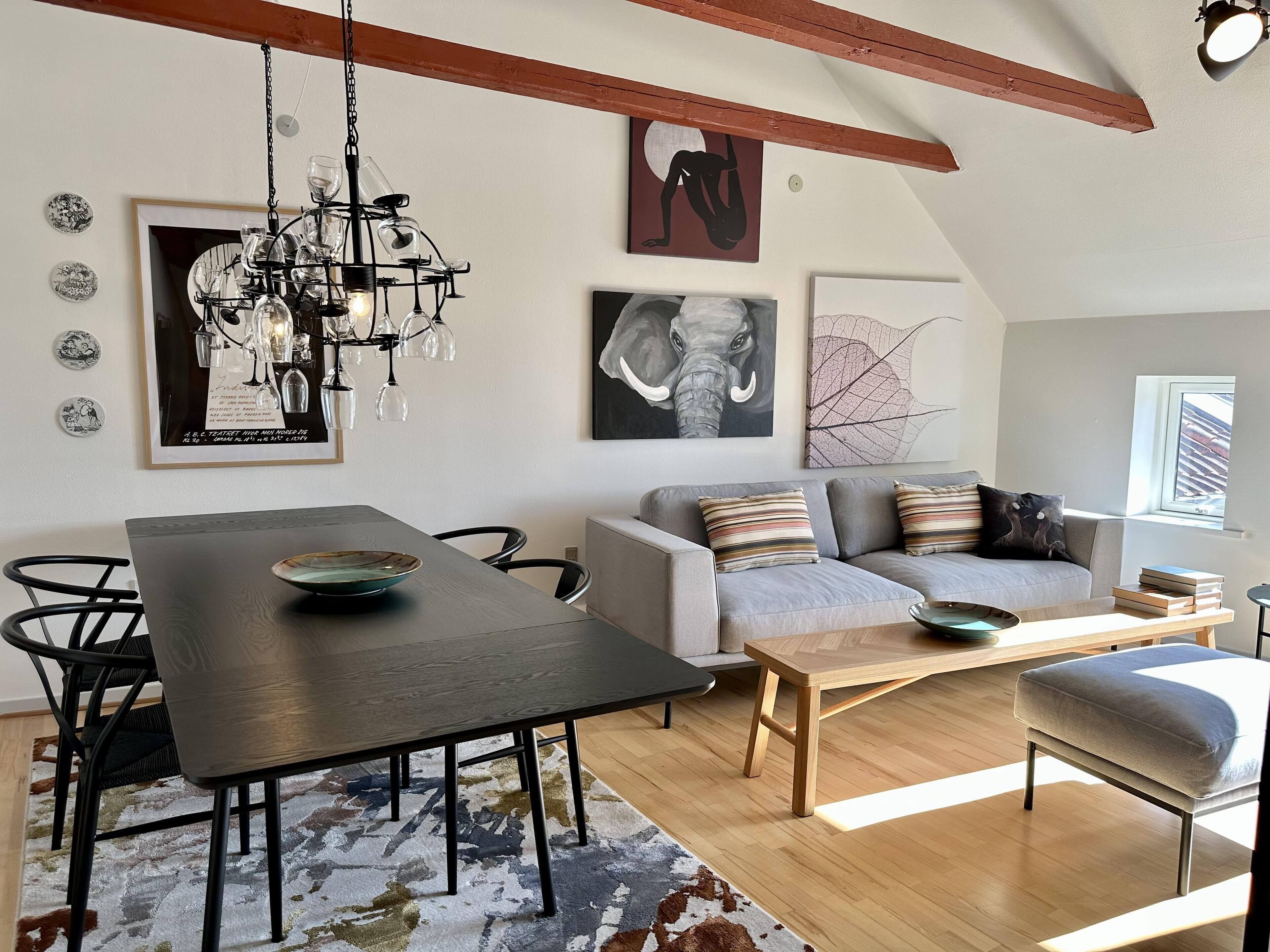 Una sala de estar moderna con una mesa de comedor, sofá y una araña.