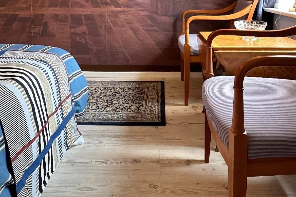 Une pièce décorée d’une fresque murale sur le thème du Moyen Âge, avec des meubles en bois et un tapis à motifs.