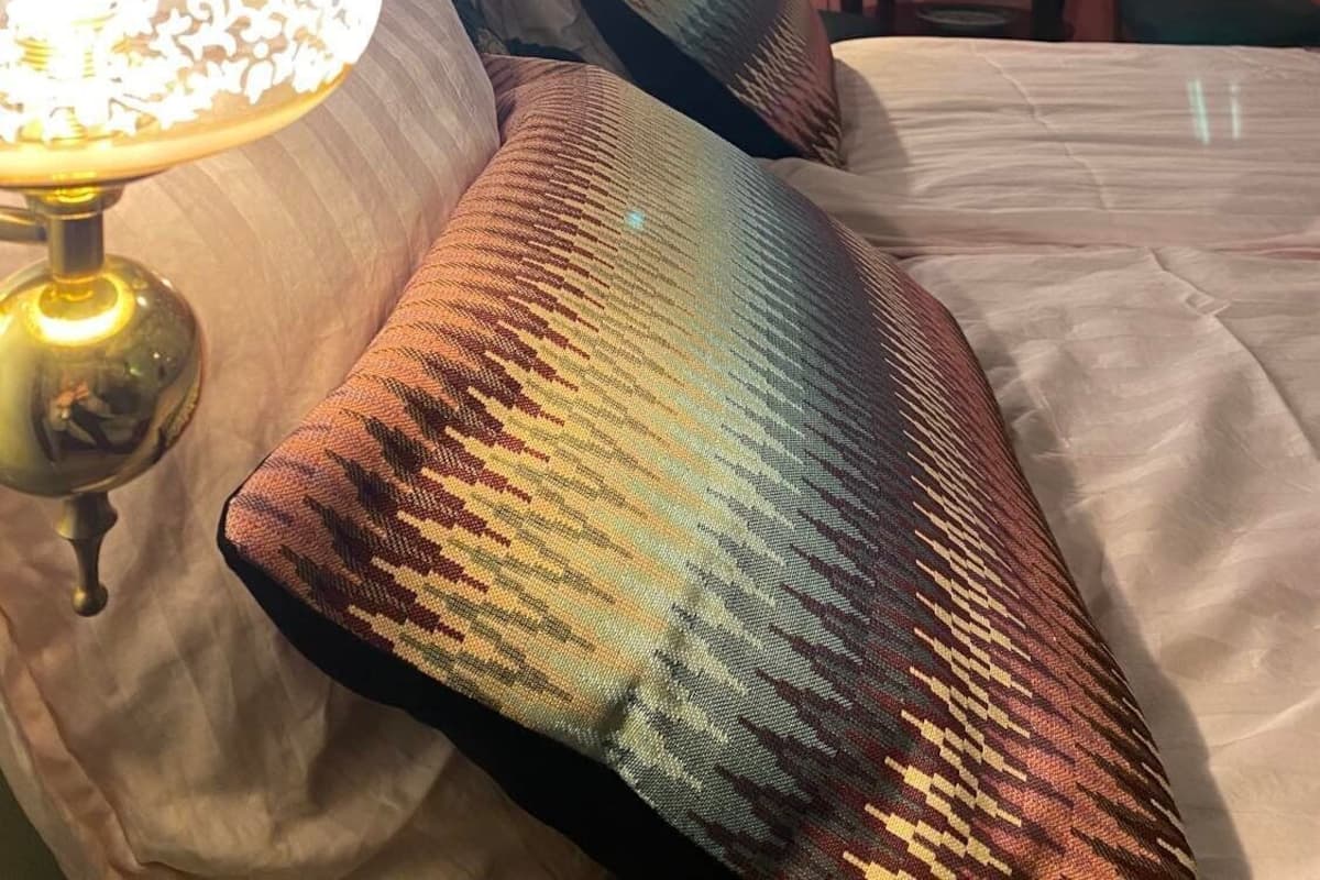 Une chambre à coucher avec un lit, des oreillers, une lampe et un mur orné d’une affiche.