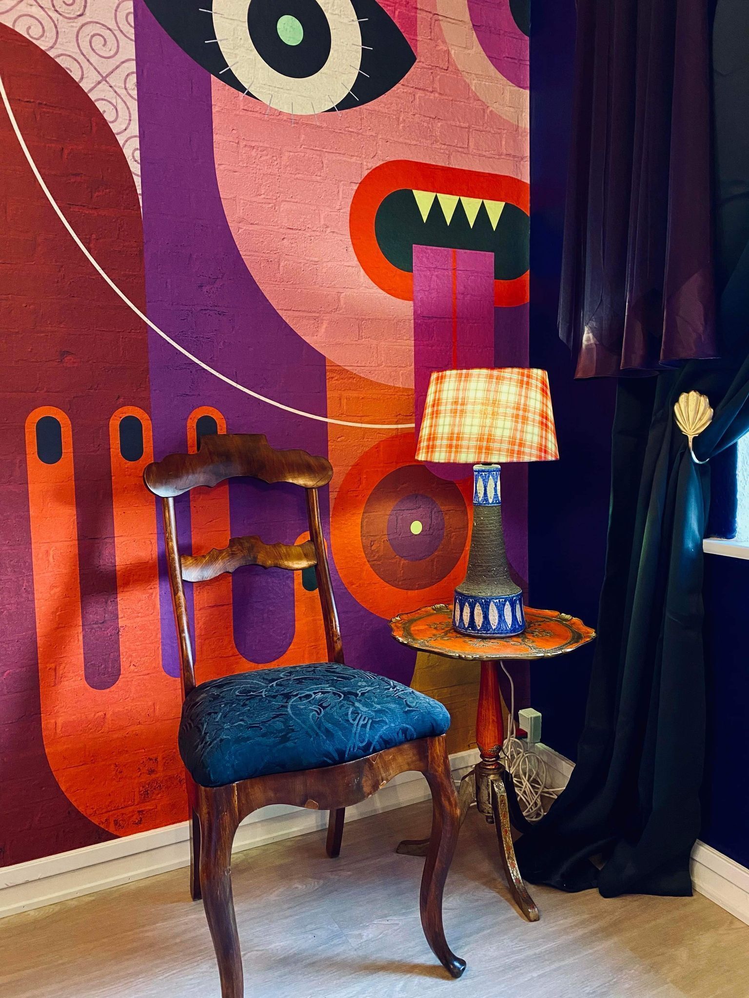 Ein Sessel mit blauer Sitzkissen und einer Lampe mit kariertem Lampenschirm.