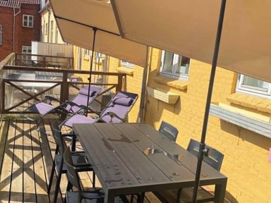 Eine Terrassenausstattung mit Tischen und Stühlen, beschattet durch Sonnenschirme, mit Holzboden.