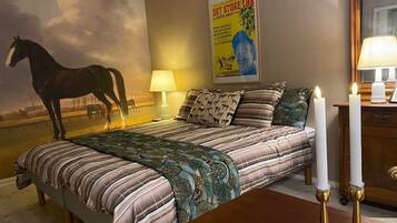 A bedroom with a bed, a lamp, a poster, and two candles.