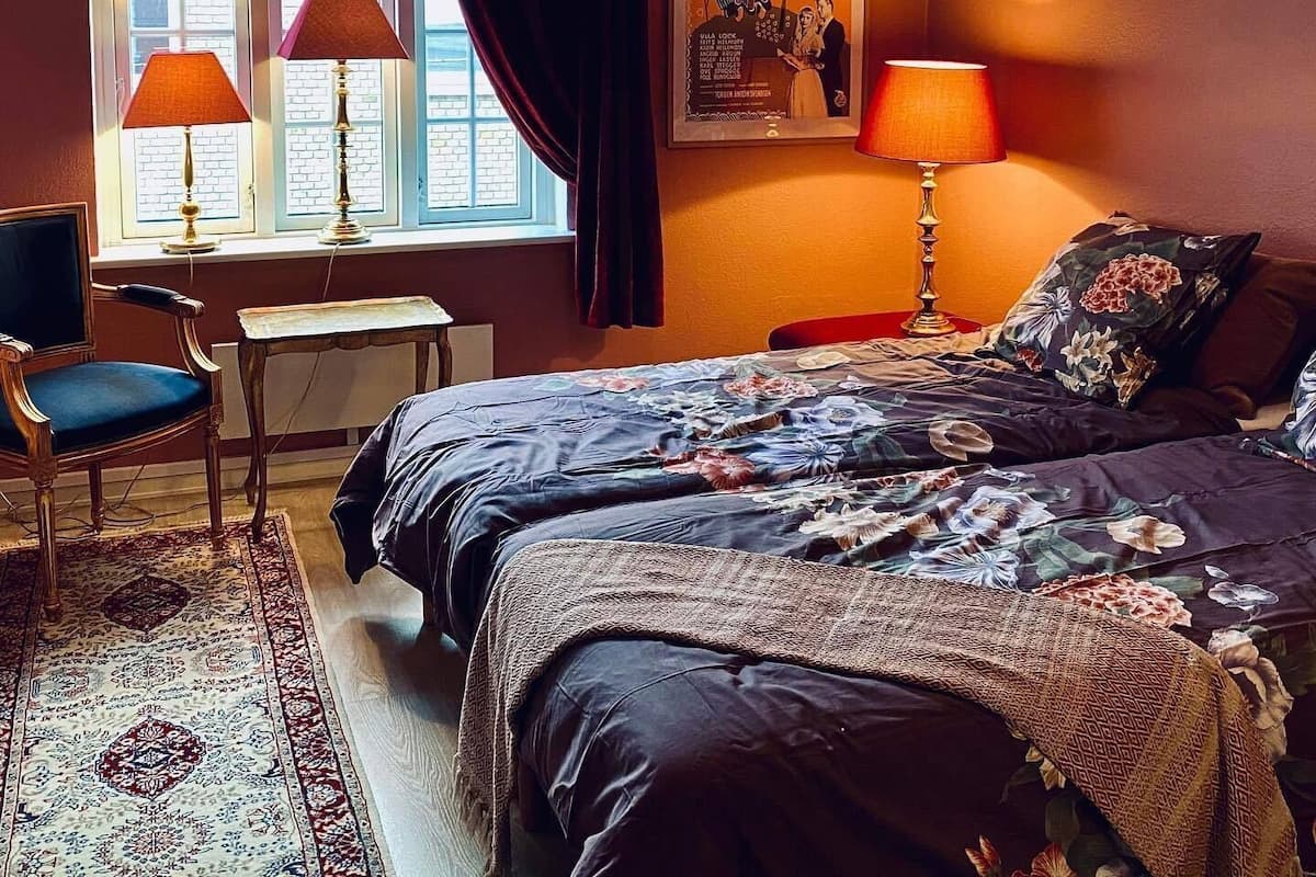 Une chambre avec une grande fenêtre, deux lits, un bureau et une chaise.