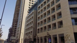 A multi-story building with a modern architectural design, featuring a prominent 'R' logo on the top. - Damac Tower studio in the center of Amman (عمّان)