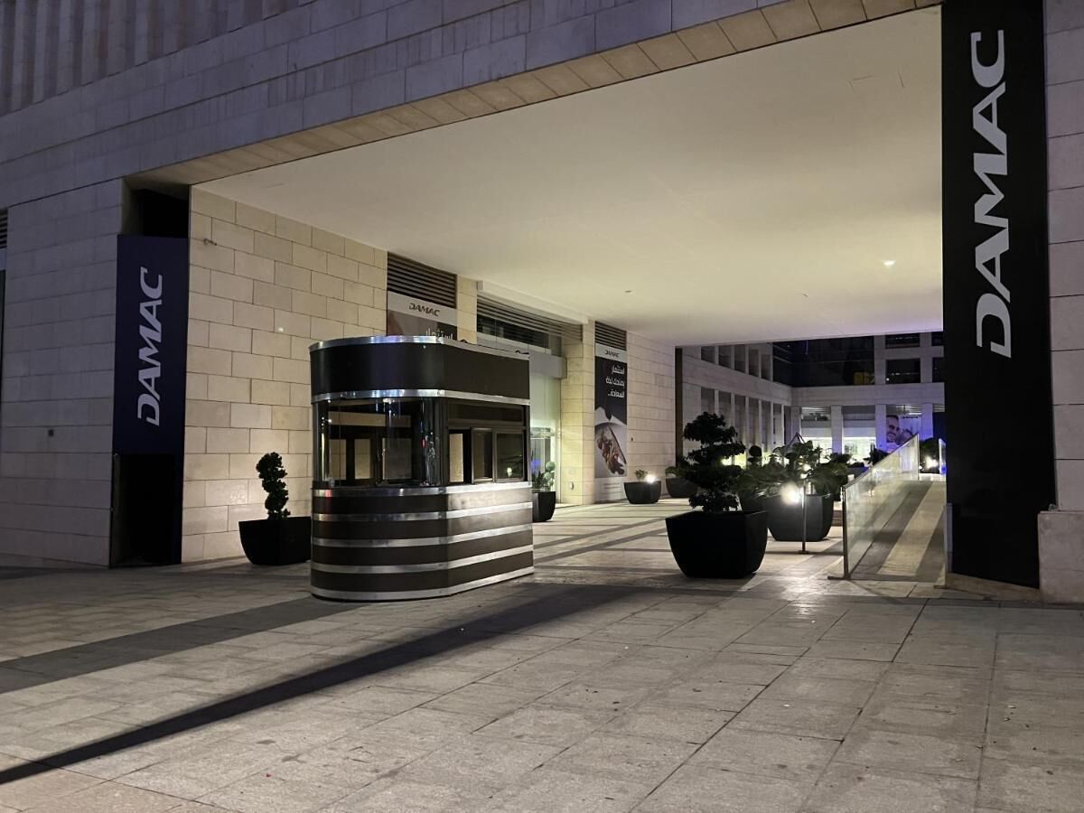 A modern building entrance with a reception desk and potted plants.