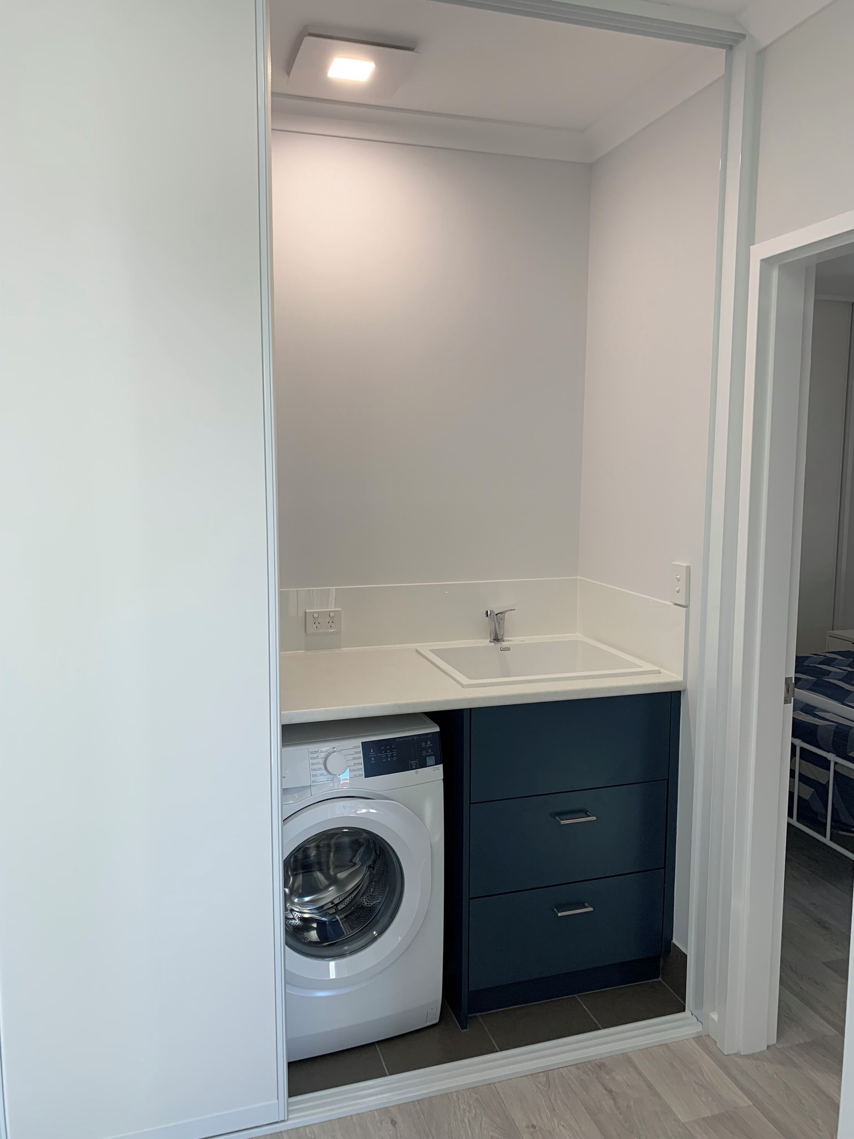 A compact laundry room with a washing machine, a sink, and a small cabinet.