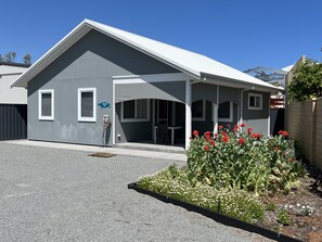 A modern building with a grey exterior and a white roof. There is a covered outdoor area with a bench and a table. - Jurien Beachfront Chalets (Jurien Bay)
