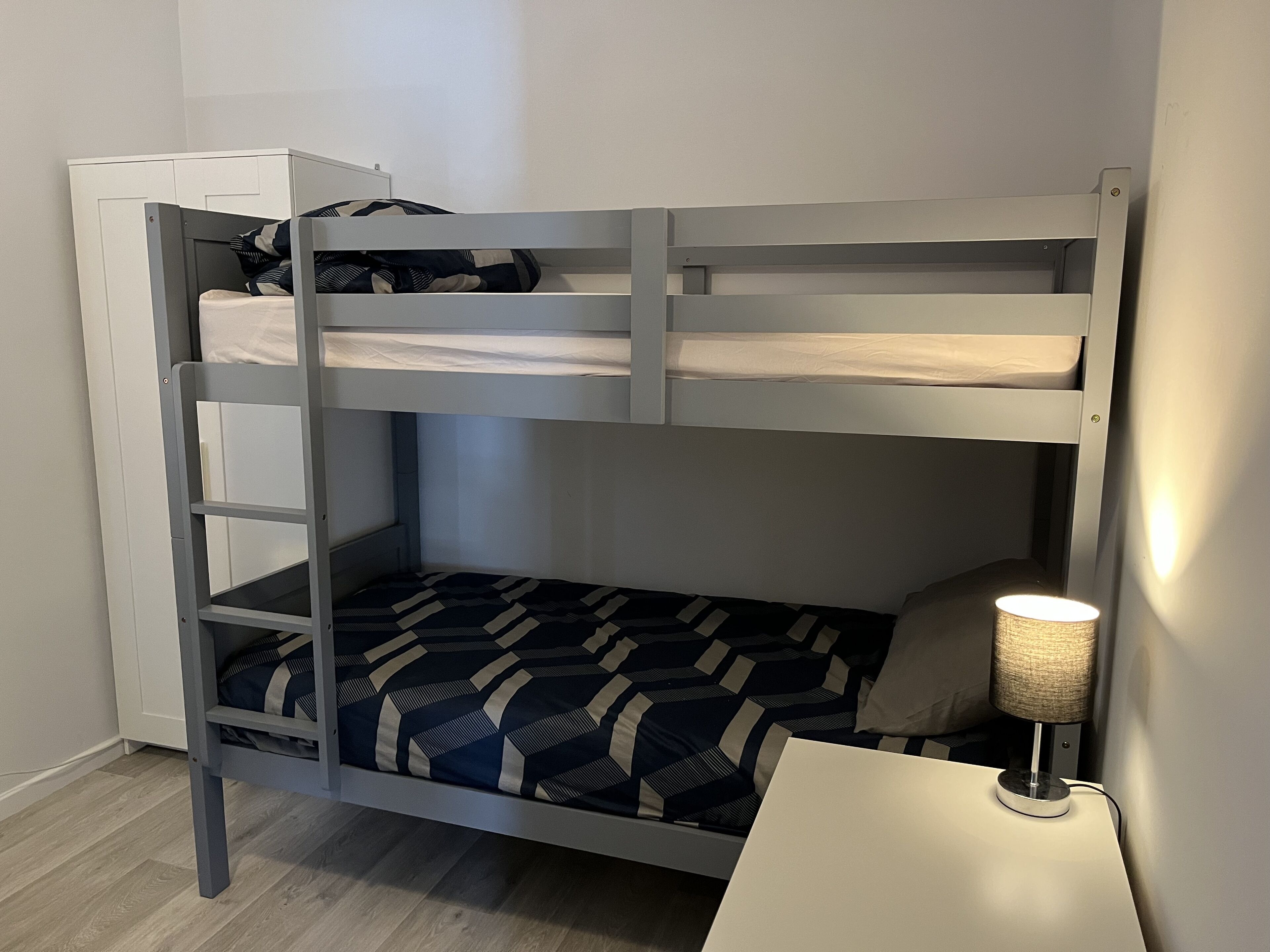 A bunk bed with a desk and a lamp.