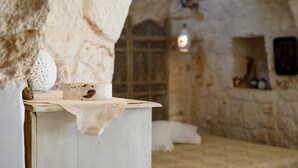 A rustic stone interior with a white table displaying a candle and a decorative item. - Trullo Letizia con Piscina by Wonderful Italy (Ostuni)