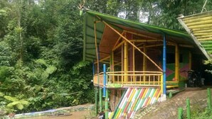 Eine rustikale Holzkonstruktion mit einem Balkon, umgeben von üppigem Grün und einem Fluss.