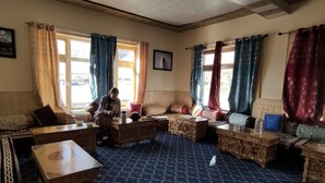 A traditional room with a patterned carpet, wooden furniture, and curtains. - Pangong Nest Cottage (Leh)