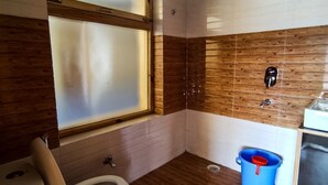 A bathroom with a wooden floor, a toilet, a window, and a blue bucket. - Pangong Nest Cottage (Leh)