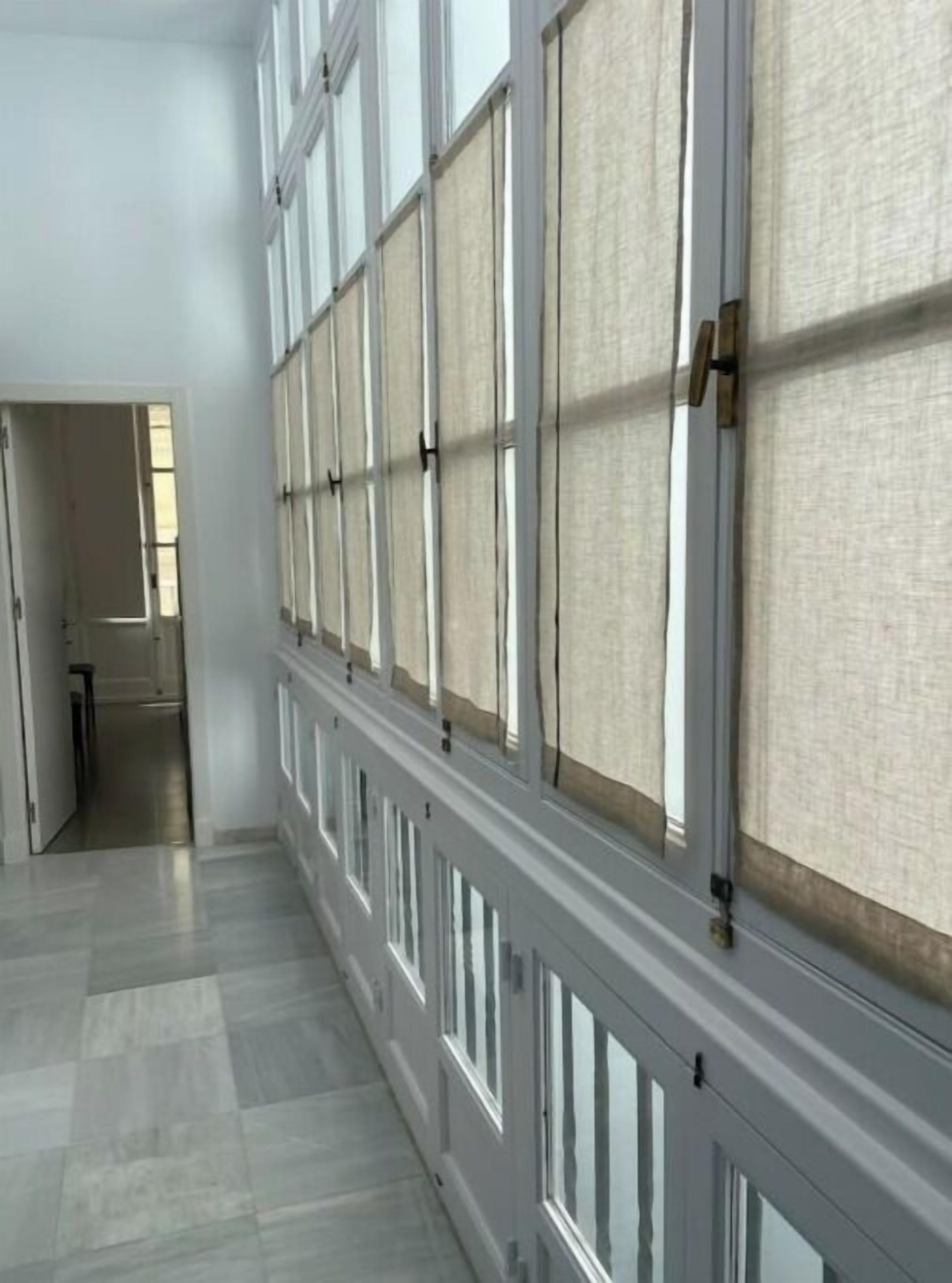 A hallway with large windows and a wooden floor.