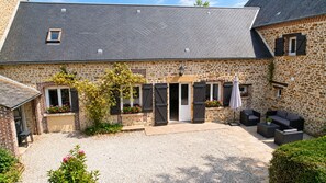 A stone building with a gravel courtyard, outdoor seating, and a covered entrance. - LONGERE N°6 (Ferrières-la-Verrerie)