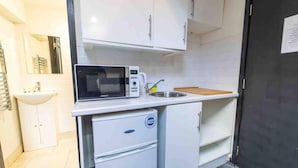 A compact kitchenette with a microwave, sink, and small refrigerator. - Ground Floor Cosy Studio Close to the City (Birmingham)