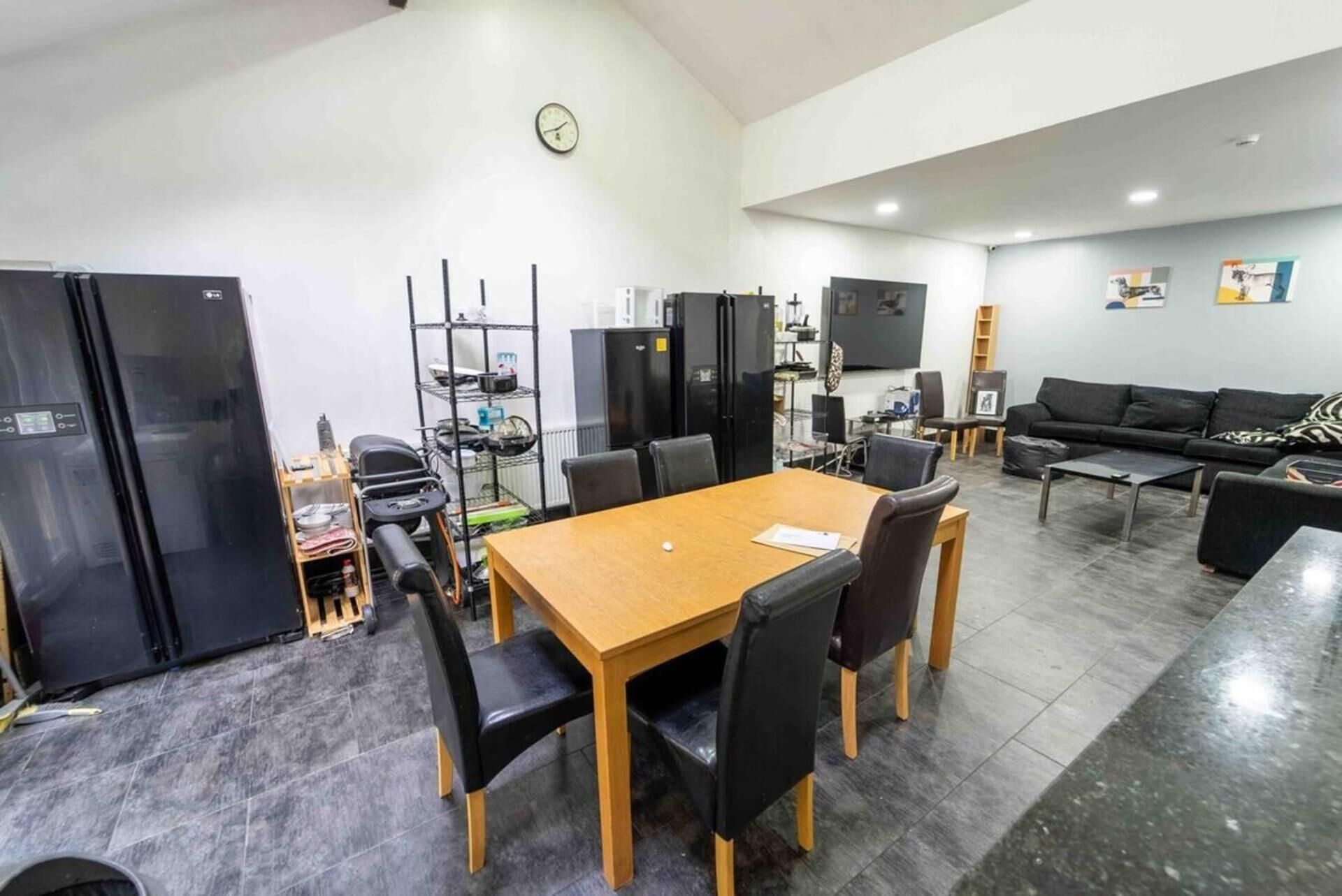Una cocina moderna con electrodomésticos negros, un comedor con mesa y sillas de madera, y una sala de estar con sofá y mesita de centro.