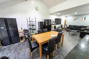 A modern kitchen with black appliances, a dining area with a wooden table and chairs, and a living area with a sofa and coffee table.