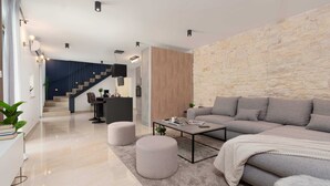 Un soggiorno moderno con un divano grigio, un tavolino da caffè e una parete decorativa in pietra.
