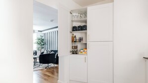 A kitchen with white cabinets, a checkered floor, and a dining area with a black chair and table. - Chic 1 Bed Flat Zone 2 Hampstead Swiss Cottage (London)
