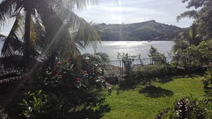 A coastal landscape with a grassy area, palm trees, and a body of water. - Les Terrasses d'Ulysse (Nosy Be)