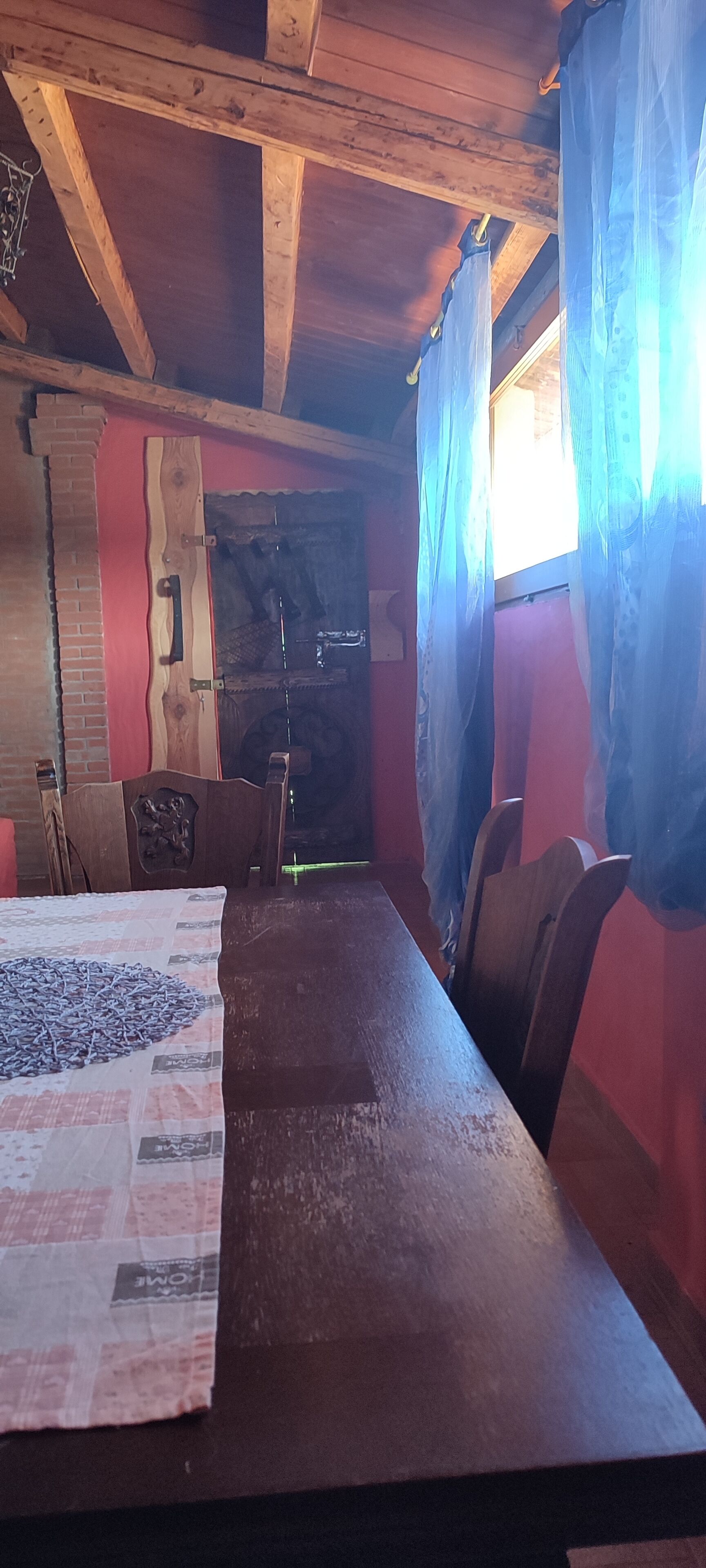 Un tavolo da pranzo in legno con sedie, una parete in mattoni e una finestra con tende.