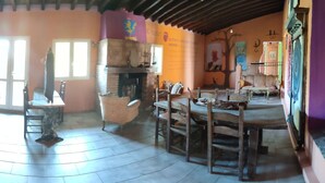 A spacious kitchen with wooden cabinets, a dining table, and chairs. There is a window providing natural light. - Il nuraghe  (Arbus)
