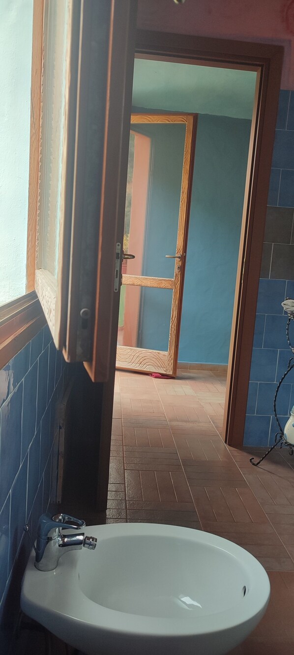 Un baño con un lavamanos blanco, paredes de azulejos azules y un marco de puerta de madera.