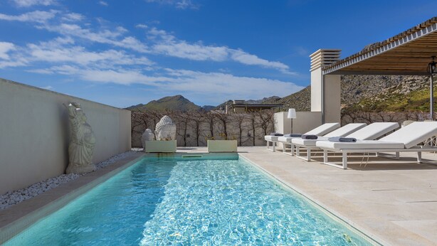 A swimming pool with lounge chairs and a pergola, surrounded by a stone wall and a view of mountains. - Penthouse  Apt Colomer by JS Villas (Port de Pollença)