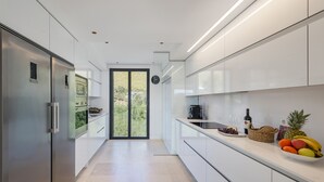 A modern kitchen with white cabinetry, a stainless steel refrigerator, and a fruit bowl on the counter. - Penthouse  Apt Colomer by JS Villas (Port de Pollença)