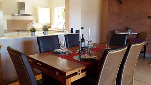 A dining area with a wooden table, black leather chairs, and a kitchen in the background. - Exclusive Finca with Pool – Away from Mass Tourism – Peaceful Location! (Triquivijate/Antigua)