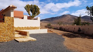 A desert landscape with a building featuring a stone wall, a cactus, and a mountain in the background. - Exclusive Finca with Pool – Away from Mass Tourism – Peaceful Location! (Triquivijate/Antigua)
