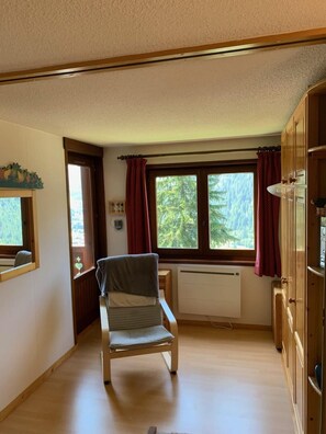 Sit comfortably in this cozy room with a chair by the window, a radiator for warmth, and a convenient cabinet for storage.