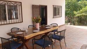 Un coin repas avec une table en bois, quatre chaises et un vase de fleurs.